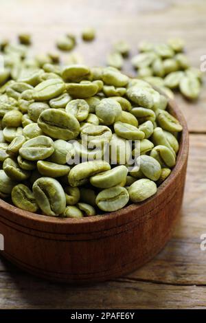 Grüne Kaffeebohnen in Schüssel auf Holztisch, Nahaufnahme Stockfoto