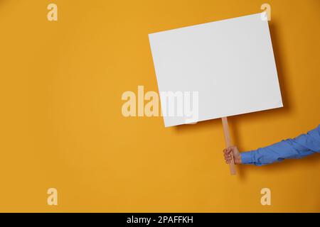 Frau mit leerem Schild auf gelbem Hintergrund, Nahaufnahme. Platz für Text Stockfoto