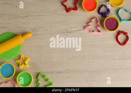 Spielteig und Werkzeuge in verschiedenen Farben auf Holztisch, flach liegend. Platz für Text Stockfoto