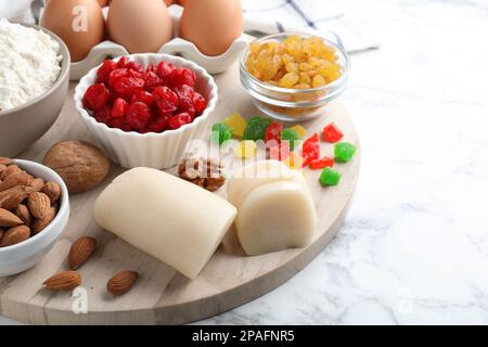 Marzipan und andere Zutaten für hausgemachtes Stollen auf einem weißen Marmortisch. Traditionelles deutsches Weihnachtsbrot backen Stockfoto