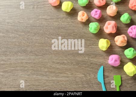 Spielteig und Werkzeuge in verschiedenen Farben auf Holztisch, flach liegend. Platz für Text Stockfoto