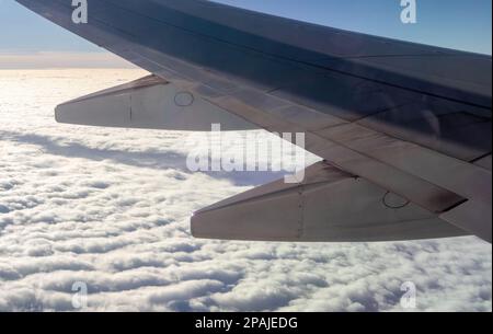 Sun Country Airlines Flugzeug fliegt über Wolken mit einem Grat in ihnen und den Horizont in der Ferne mit wunderschönem blauen Himmel; mit dem Flugzeugflügel. Stockfoto