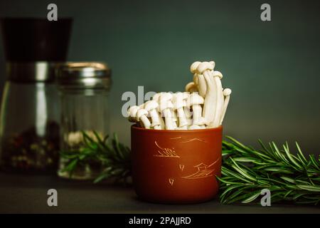 Frische rohe weiße Shimiji-Shimeji-Pilze in brauner Schüssel Hypsizygus tessulatus Asia-Pilze. Vegetarische vegane asiatische gesunde Lebensmittel. Buche-Pilzrücken Stockfoto