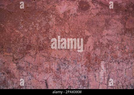 Die Textur einer alten rustikalen Wand ist mit rosa Stuck bedeckt Stockfoto