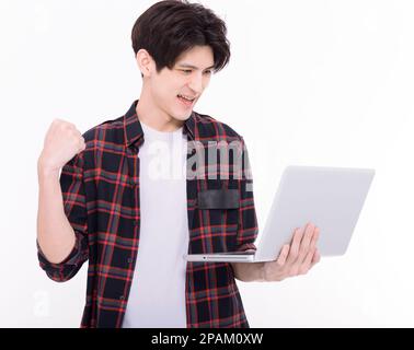 Glücklicher junger Mann, der den Laptop festhält und ja-Gesten zeigt Stockfoto