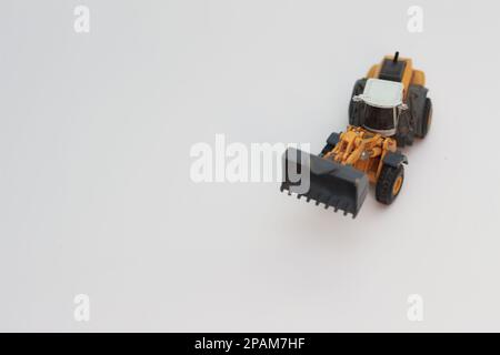 Nahaufnahme eines orangefarbenen Miniatur-Spielzeugs mit Radlader, isoliert auf weißem Hintergrund. Konzeptfoto eines schweren Miniaturspielzeugs. Stockfoto