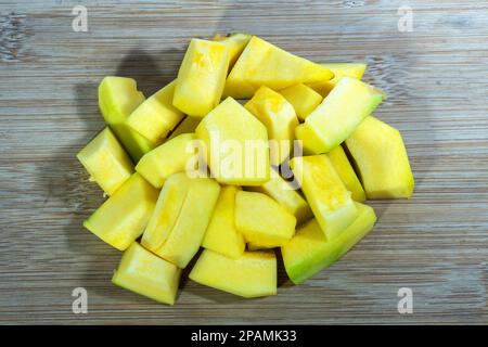 Rohe, von Kürbissen geschnittene Würfel auf Holzschneidplatte auf Tischhintergrund Stockfoto