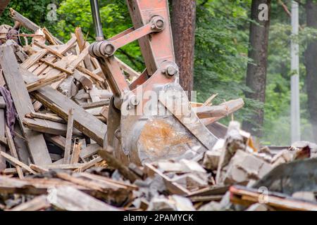 Baggerlöffel lädt Bauschutt nach dem Abriss des alten Gebäudes Stockfoto