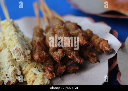 Foto: Satay-Hähnchen mit Spiegelei und Satay-Hähnchendarm, serviert mit roter Chilisauce. Indonesisches Essen namens Sate Taichan. Essenskonzert Stockfoto