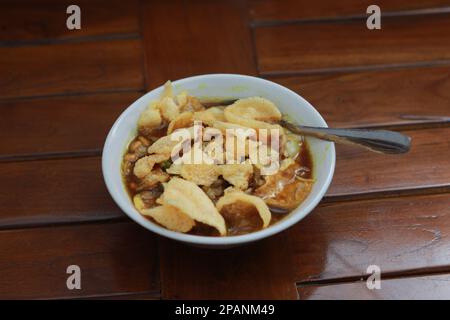 Nahaufnahme einer servierfertigen Schüssel mit Hähnchenporridge mit natürlich gemustertem Holzhintergrund. Indonesisches Lebensmittelkonzept. Stockfoto