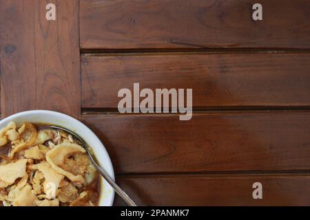 Nahaufnahme einer servierfertigen Schüssel mit Hähnchenporridge mit natürlich gemustertem Holzhintergrund. Indonesisches Lebensmittelkonzept. Stockfoto