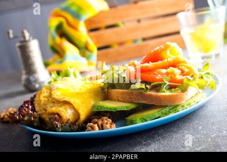 Omelette oder Omelette, frischer Rucola- und Tomatensalat und Toast mit Butter und gesalzenem Lachs. Frühstück. Draufsicht Stockfoto