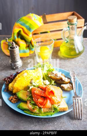 Omelette oder Omelette, frischer Rucola- und Tomatensalat und Toast mit Butter und gesalzenem Lachs. Frühstück. Draufsicht Stockfoto