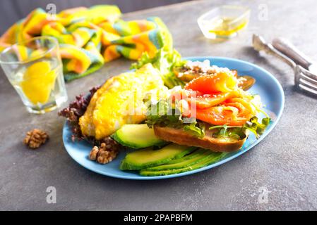 Omelette oder Omelette, frischer Rucola- und Tomatensalat und Toast mit Butter und gesalzenem Lachs. Frühstück. Draufsicht Stockfoto