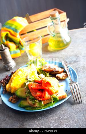 Omelette oder Omelette, frischer Rucola- und Tomatensalat und Toast mit Butter und gesalzenem Lachs. Frühstück. Draufsicht Stockfoto