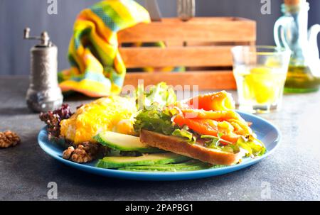 Omelette oder Omelette, frischer Rucola- und Tomatensalat und Toast mit Butter und gesalzenem Lachs. Frühstück. Draufsicht Stockfoto