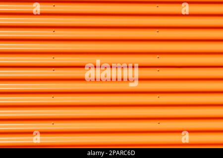 Wand aus Streifen mit Aluminiumprofil in orangefarbener Farbe. Horizontale parallele Linien. Stockfoto