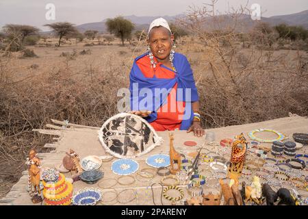 Karatu, Tansania - 16. Oktober 2022: Porträt einer masai-Frau in traditioneller Kleidung und Schmuck, die afrikanische Souvenirs von thor aus ihrem Dorf verkauft Stockfoto
