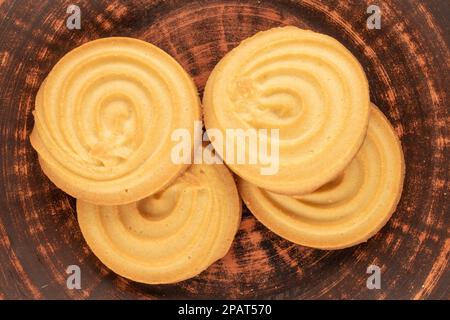 Vier süße Kekse auf einer Tonuntertasse, Makro, Draufsicht. Stockfoto