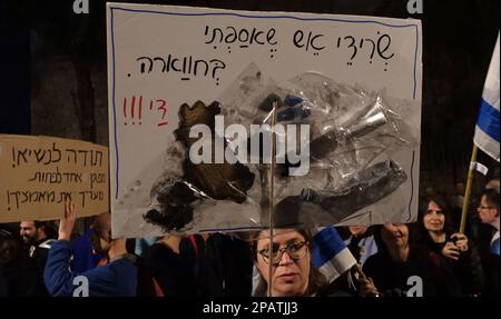 JERUSALEM, ISRAEL - MÄRZ 11: Musik wird gespielt, während ein Demonstrant ein Schild mit der Aufschrift "Relikte des Feuers, die ich von Huwara gesammelt habe" während einer Demonstration gegen Israels neuen Plan des Justizsystems hält, der darauf abzielt, den Obersten Gerichtshof des Landes außerhalb der Residenz des Präsidenten am 11. März 2023 in Jerusalem, Israel, zu schwächen. Kredit: Eddie Gerald/Alamy Live News Stockfoto