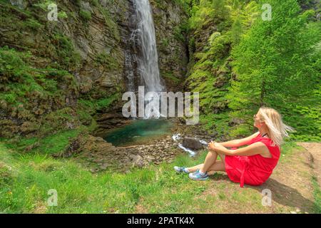 Frau, die sich nach einer Wanderung im Wald von Sonogno zum Froda-Wasserfall am Riale Carded River ausruht. Die Schweizer Stadt Sonogno im Verzasca-Tal in Stockfoto