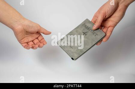 Die Frauenhand erhält den Reisepass von der anderen Männerhand. Stockfoto