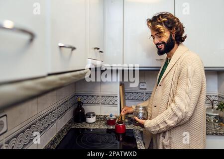 Junger Mann, der zu Hause in der Küche Kaffee zubereitet Stockfoto