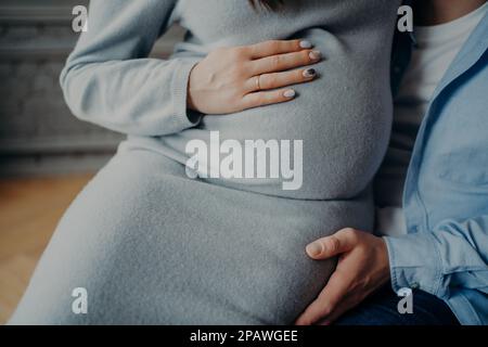 Schwangere Frau und ihr Mann warten darauf, dass das Baby glückliche Eltern werden wird. Schwangerschafts-Liebes-Familien-Beziehungskonzept. Zugeschnittenes Bild Stockfoto