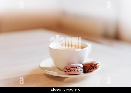 Eine Tasse Cappuccino-Kaffee, Makkaroni-Kuchen auf einem Tisch. Konzept von Frische und angenehmer Kühlung an einem heißen Tag. Karamellmakronen. Light flatley mit Stockfoto