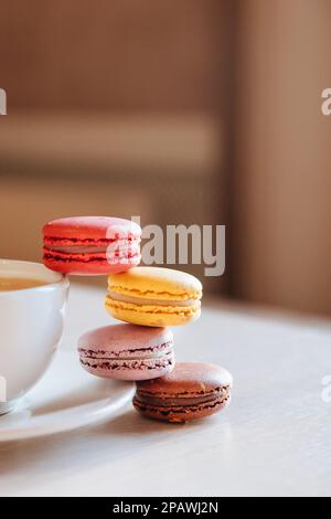 Eine Tasse Cappuccino-Kaffee, Makkaroni-Kuchen auf einem Tisch. Konzept von Frische und angenehmer Kühlung an einem heißen Tag. Karamellmakronen. Light flatley mit Stockfoto