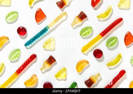 Kauende Marmelade verschiedener Formen, Geschmacksrichtungen und Farben liegt in einem Muster auf weißem Hintergrund. Freier Platz in der Mitte Stockfoto