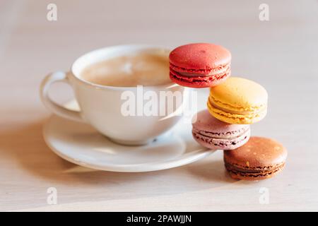 Eine Tasse Cappuccino-Kaffee, Makkaroni-Kuchen auf einem Tisch. Konzept von Frische und angenehmer Kühlung an einem heißen Tag. Karamellmakronen. Light flatley mit Stockfoto