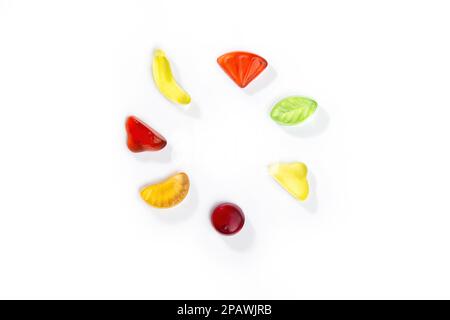 Gummibonbons in Form von Früchten und Beeren liegen in einem Kreis auf weißem Hintergrund. Stockfoto