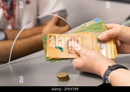 Costa Rica Geld, Eine Frau steht an der Kasse mit viel Bargeld in der Hand, Konzept, Bareinzahlung und -Abhebung, Finanzoperationen, Bank Stockfoto