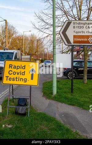 Temporäres gelbes Straßenschild mit Richtungspfeil zum Covid-Schnelltestzentrum Stockfoto