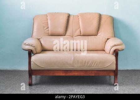 1950er beiges Ledersofa mit 2 Sitzen in einem einfachen Wohnzimmer in einem gemütlichen Apartment Stockfoto