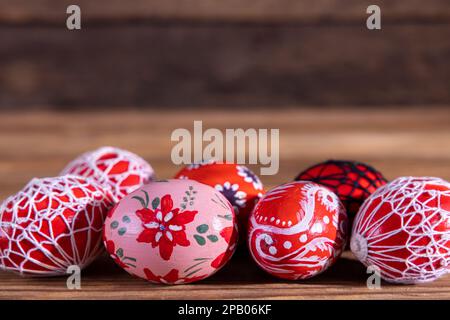 Ostereier in roten Schattierungen, die auf alten Brettern hintereinander angeordnet sind. Stockfoto