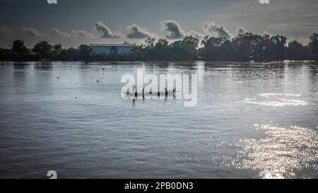 Zwei Fischer, die auf ihrem kleinen traditionellen Holzboot auf dem Mekong in der Provinz Kandal, Kambodscha, arbeiten. Stockfoto