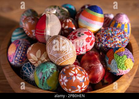 Eine Holzschüssel mit eng angeordneten Ostereiern steht auf einem Hintergrund mit Brettern. Stockfoto