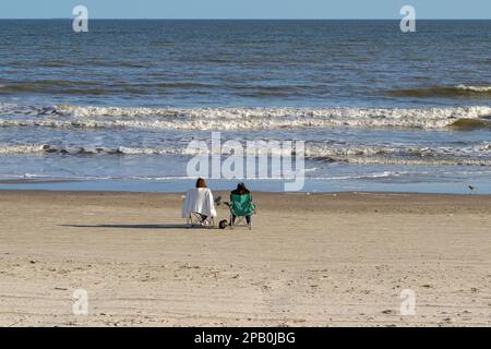 Galveston, Texas, USA - Februar 2023: Zwei Personen entspannen sich auf Stühlen am Ufer mit Blick auf das Meer Stockfoto