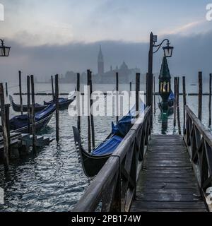 Venedig, Italien - 15. November 2022: Morgenblick auf Gondeln, den Canale Grande und den Glockenturm San Giorgio Stockfoto