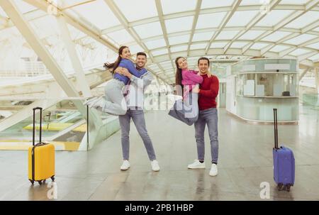 Zwei Fröhliche Paare, Die Urlaub Feiern Und Sich Am Flughafen Amüsieren Stockfoto