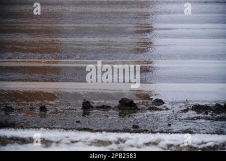 Schmutzige Pfützen auf Asphaltstraßen durch geschmolzenen Schnee im Frühling Stockfoto