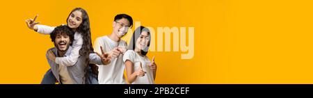 Positive asiatische und indische Paare, die Spaß an Gelb haben Stockfoto