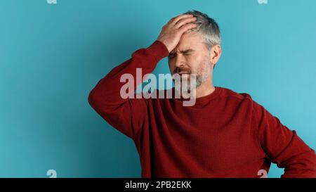 Ein Mann mittleren Alters mit grauhaarigem Bart berührt den Kopf Stockfoto