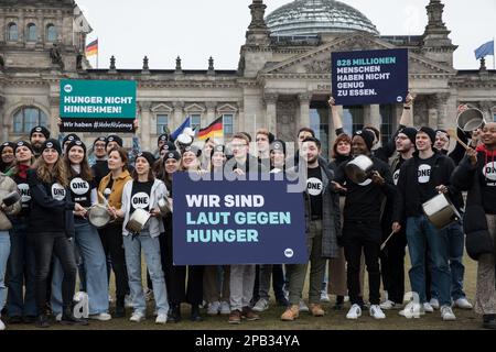 12. März 2023, Berlin, Deutschland: Am 12. März 2023 protestierte eine Gruppe junger Menschen vor dem Reichstag in Berlin, um darauf aufmerksam zu machen, dass weltweit noch 828 Millionen Menschen Hunger leiden. Sie trommelten auf Töpfen und hielten Schilder mit dem Slogan „laut gegen Hunger“. Die ONE Campaign, auch BEKANNT als ONE, ist eine internationale, nicht-parteiische, gemeinnützige Organisation, die sich für die Bekämpfung extremer Armut und vermeidbarer Krankheiten, insbesondere in Afrika, einsetzt, indem sie die Öffentlichkeit sensibilisiert und politische Führer unter Druck setzt, Strategien und Programme zu unterstützen, die sav unterstützen Stockfoto