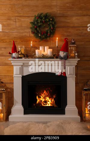 Süße Weihnachtszwerge und festliche Dekorationen am Kamin im Zimmer Stockfoto