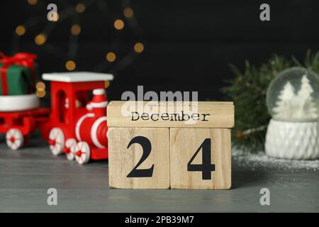 Dezember 24 - Heiligabend. Holzkastenkalender und Tischdekor vor verschwommenen festlichen Lichtern Stockfoto