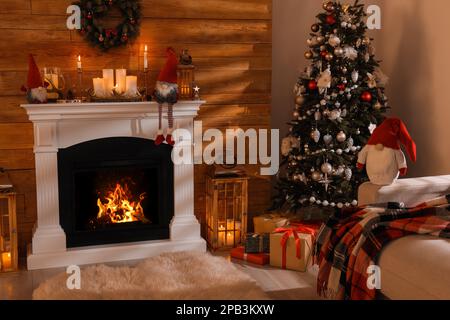 Süße Zwerge und Weihnachtsbaum im Zimmer mit festlicher Dekoration Stockfoto