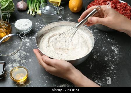 Eine Frau, die leckere Gyoza am schwarzen Tisch kocht, Nahaufnahme Stockfoto